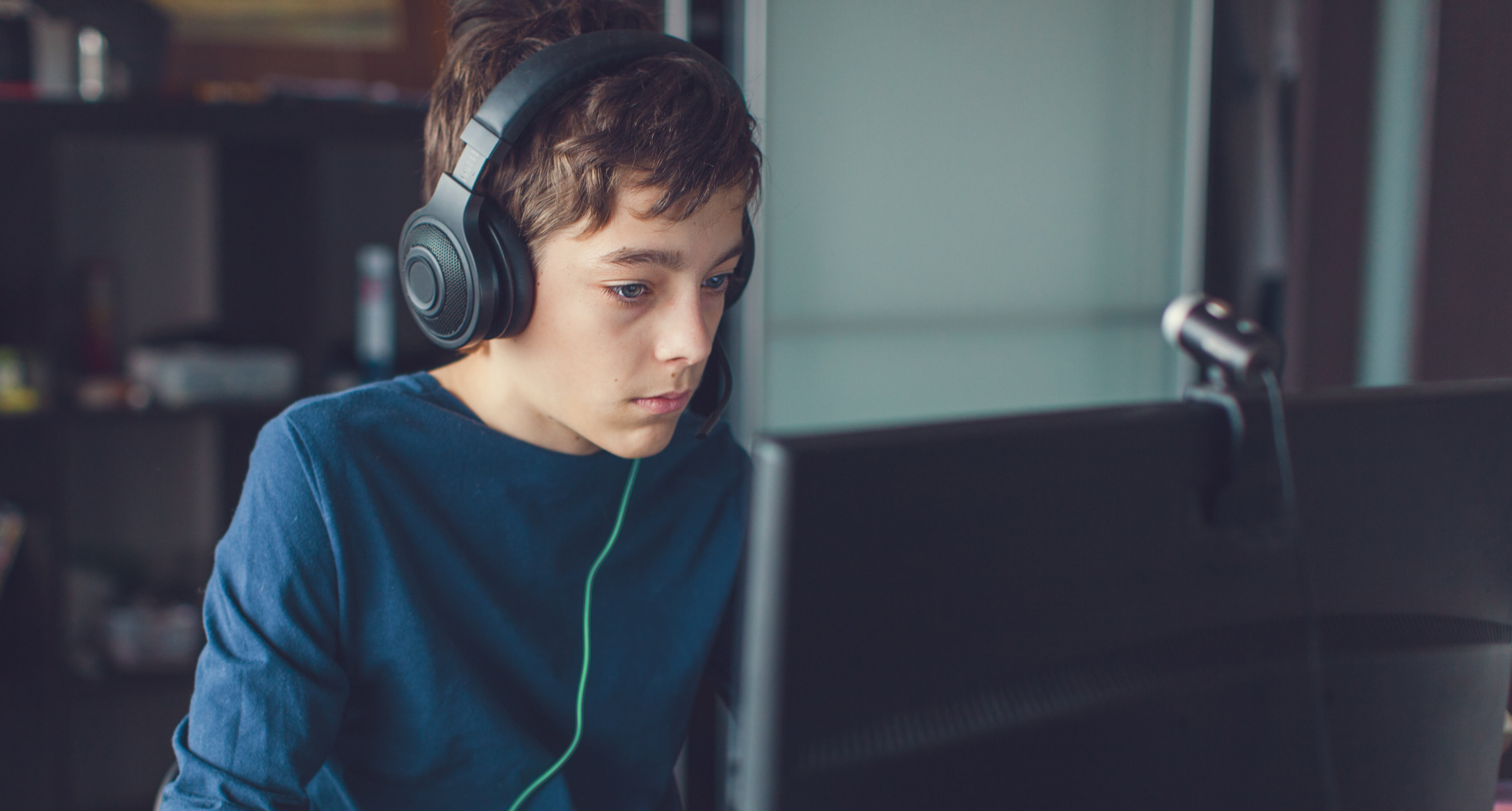 Kind mit Kopfhörern das gespannt auf einen Maptop schaut