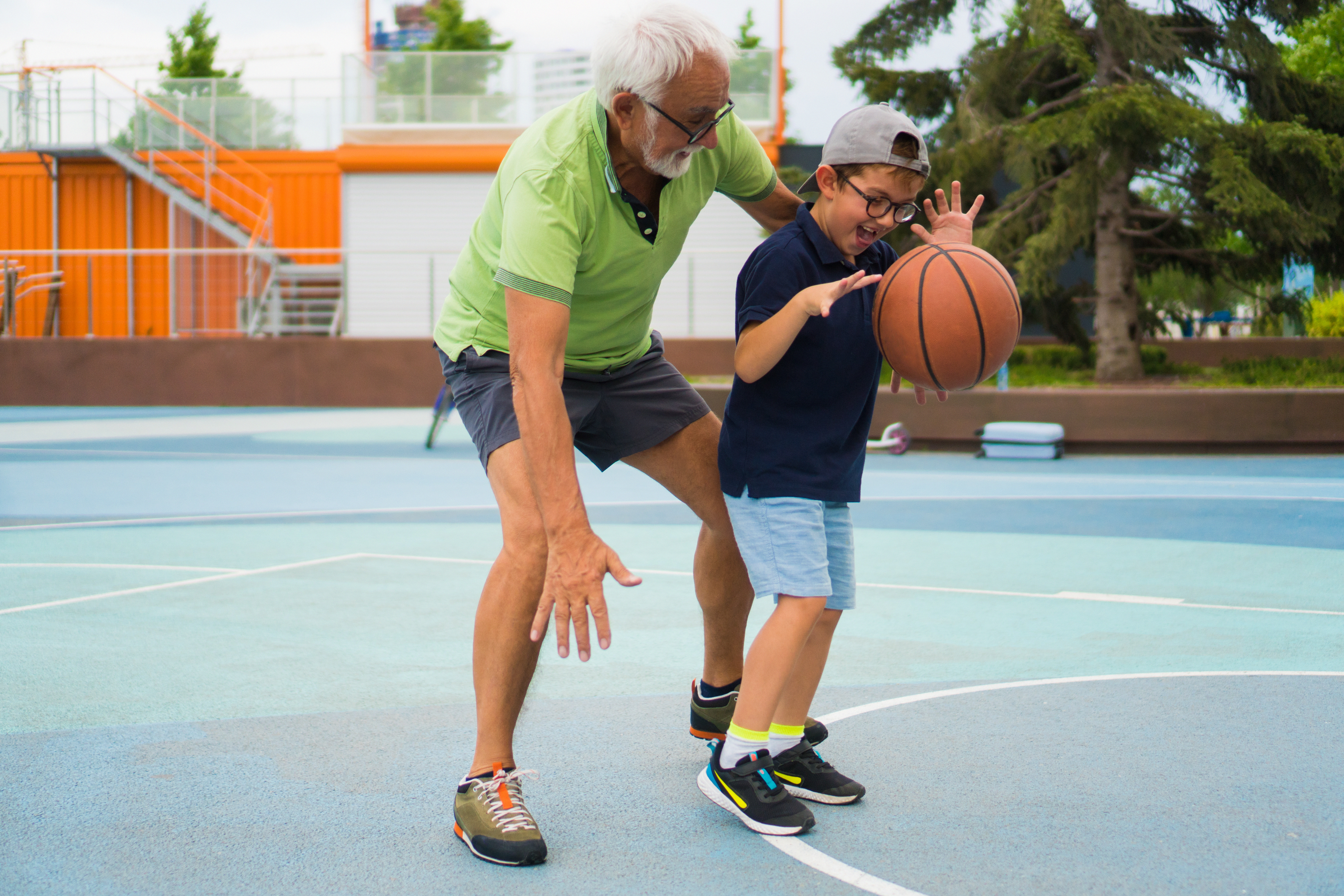Älterer Mann und Junge spielen Basketball