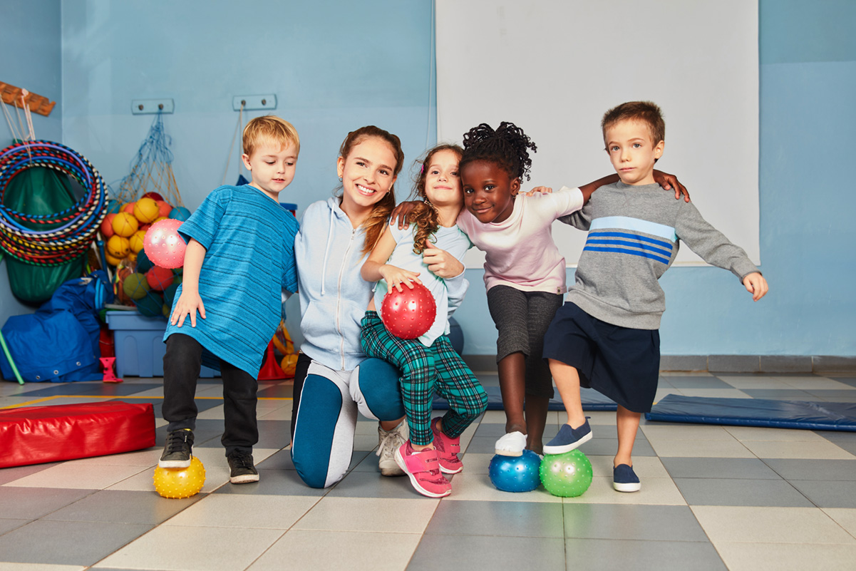 Lehrerin und Kinder Gruppe mit Bällen KiB-mobil